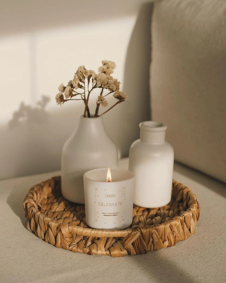 A setup with a scented candle, ceramic vases, and dried flowers placed on a woven tray, styled by an Interior Designing Company in Malappuram