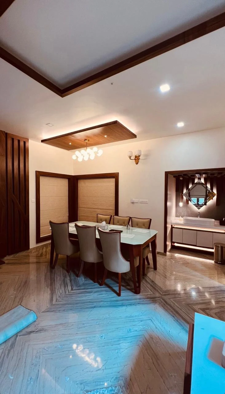 “A modern dining room with elegant wooden finishes, stylish ceiling lights, and a table setup, designed by an Interior Designing Company in Malappuram.